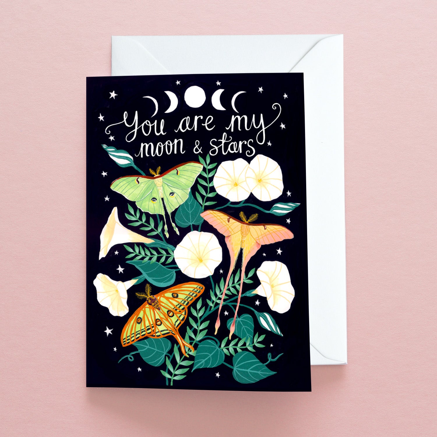 The Papio Press You Are My Moon & Stars Greetings Card features three colorful moths, white flowers, and green leaves on a dark background with moon phases. Printed on recycled stock, it reads You are my moon & stars.