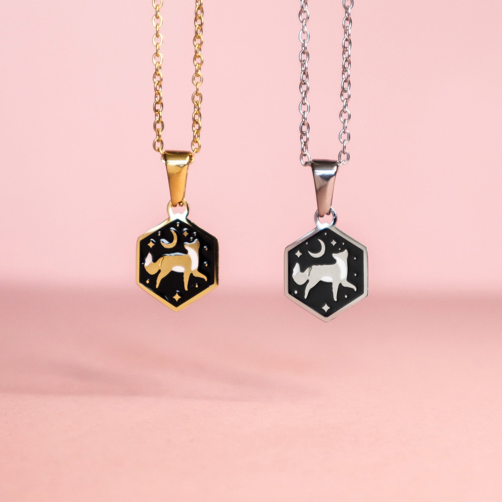 Two Mini Hexagon Fox Pendants by Papio Press, featuring fox designs on gold and silver stainless steel chains, are displayed against a soft pink surface.