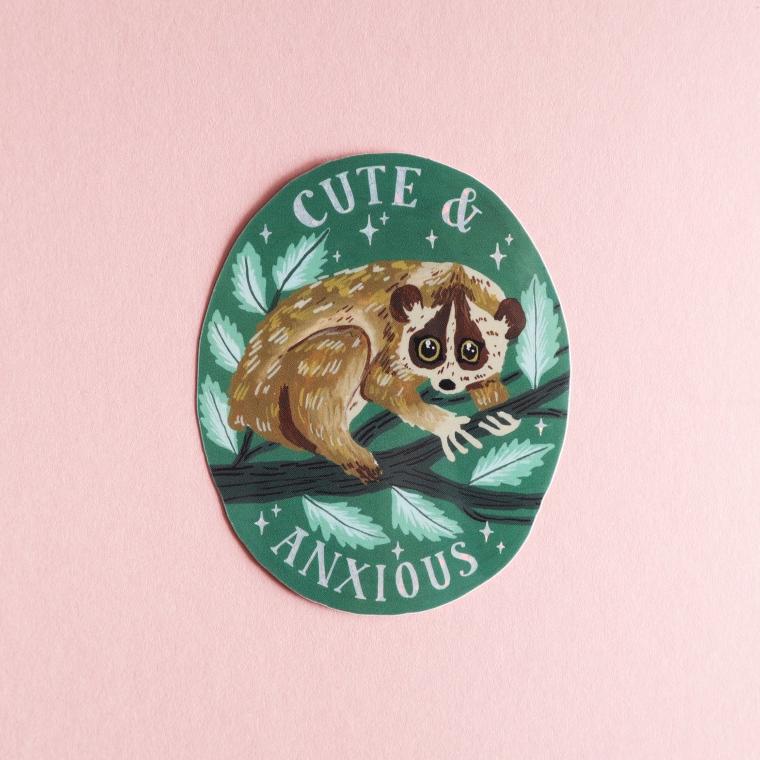 The Papio Press Cute & Anxious Slow Loris Sticker features a wide-eyed slow loris on a leafy green background with glossy finish, clinging to a branch with CUTE & ANXIOUS text above and below.
