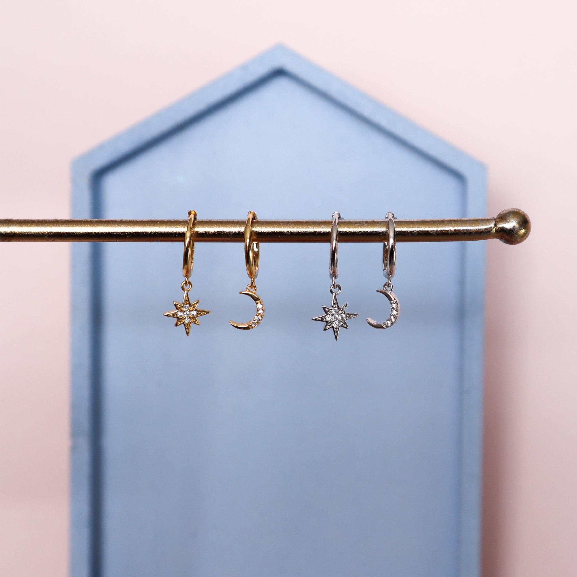 Two pairs of Celestial Moon and Star hoop earrings, one gold and one silver.