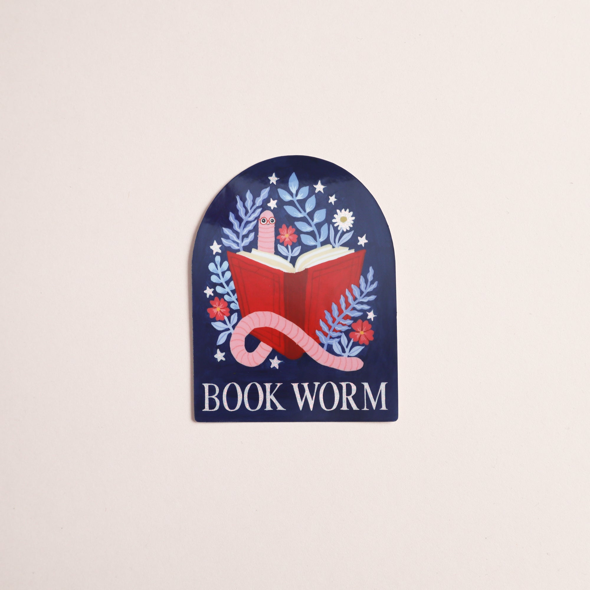 The Book Worm Reading Sticker by Papio Press features a glossy finish and shows a red book with flowers, leaves, and a pink worm on a dark blue background with BOOK WORM text—perfect for any book lover.