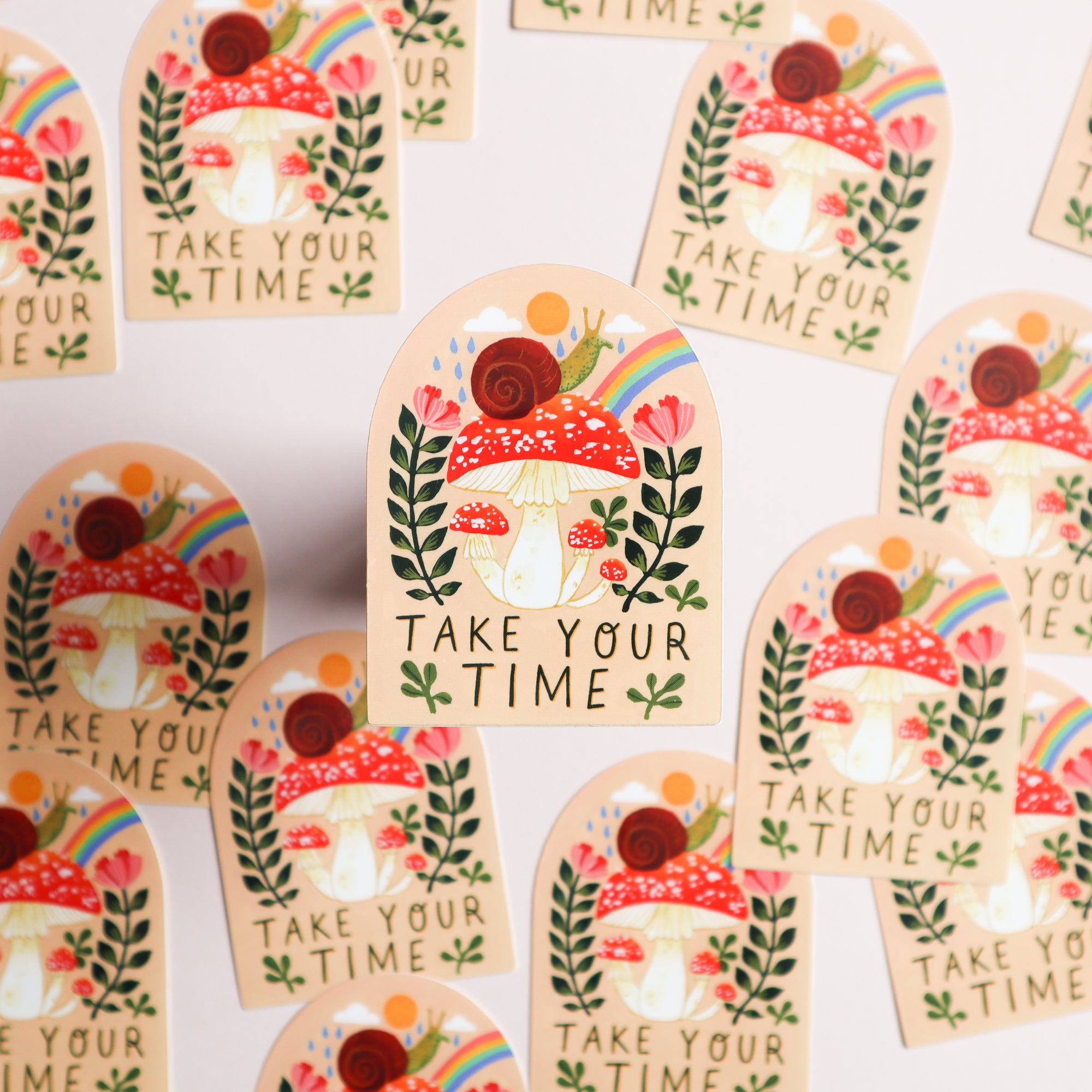 Papio Presss Take Your Time Snail Sticker features a red mushroom with a snail, plants, and a rainbow, plus Take Your Time text. These glossy UV-protected vinyl stickers are shown scattered on a white background.
