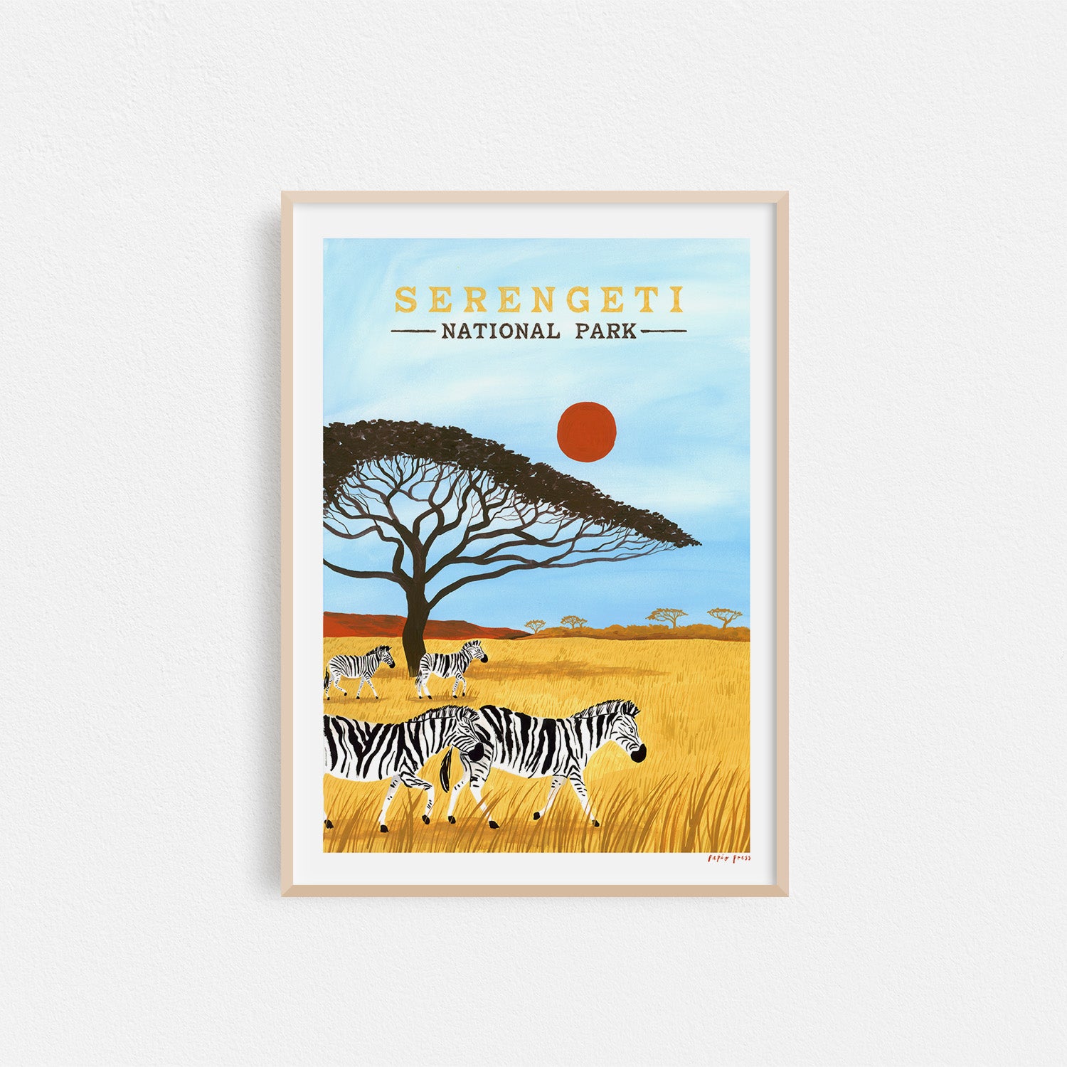 The Serengeti National Park Artists Print by Papio Press features zebras in tall grass, an acacia tree, red sun, and blue sky, printed as an inkjet print on archival satin paper.