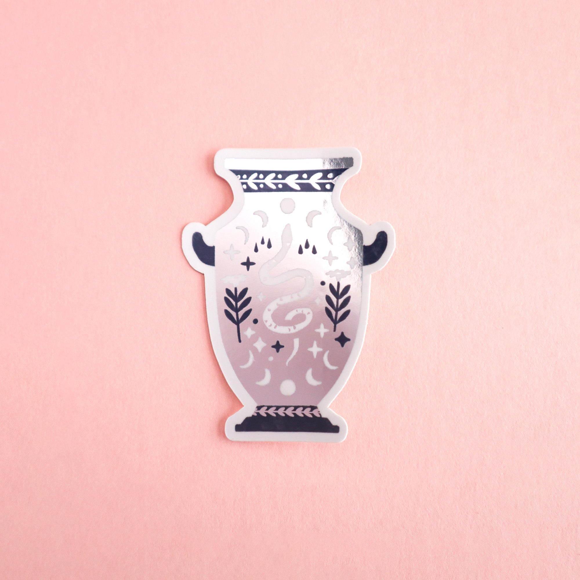 A Papio Press sticker from the Set of Three: Unicorn, Dragon & Snake Vase Stickers, featuring a decorative vase with dark handles, leafy motifs, crescent moons, metallic accents, and a coiled snake on a light pink background.