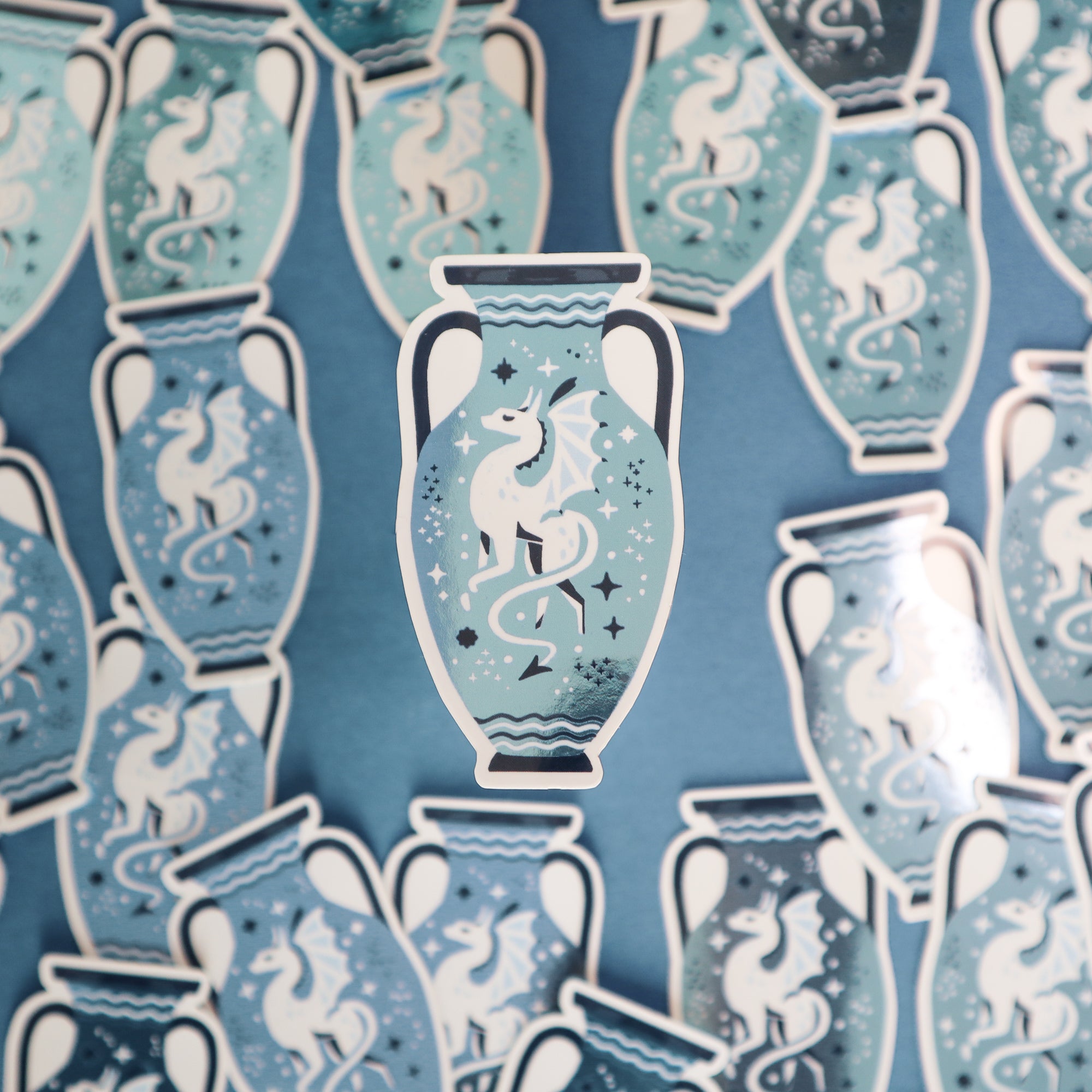 Papio Press’s Set of Three Vase Stickers—Unicorn, Dragon & Snake—features a blue vase with a white, winged dragon and subtle metallic details, spread out with one sticker centered on a blue background.