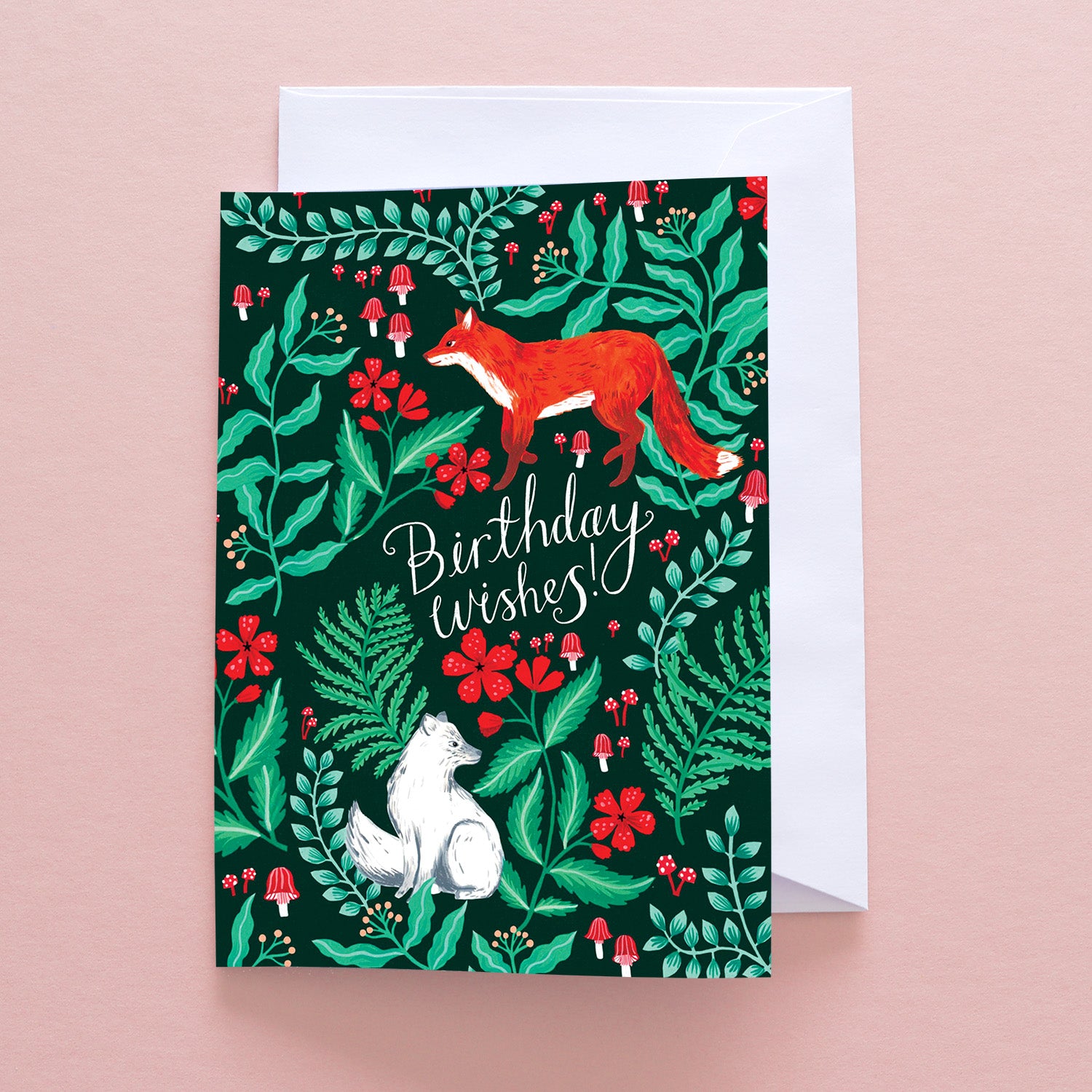 Papio Press Birthday Wishes Foxes Greetings Card features a red fox and white squirrel among green leaves, red flowers, and mushrooms on a dark background. Printed on recycled stock with Birthday wishes! in cursive.