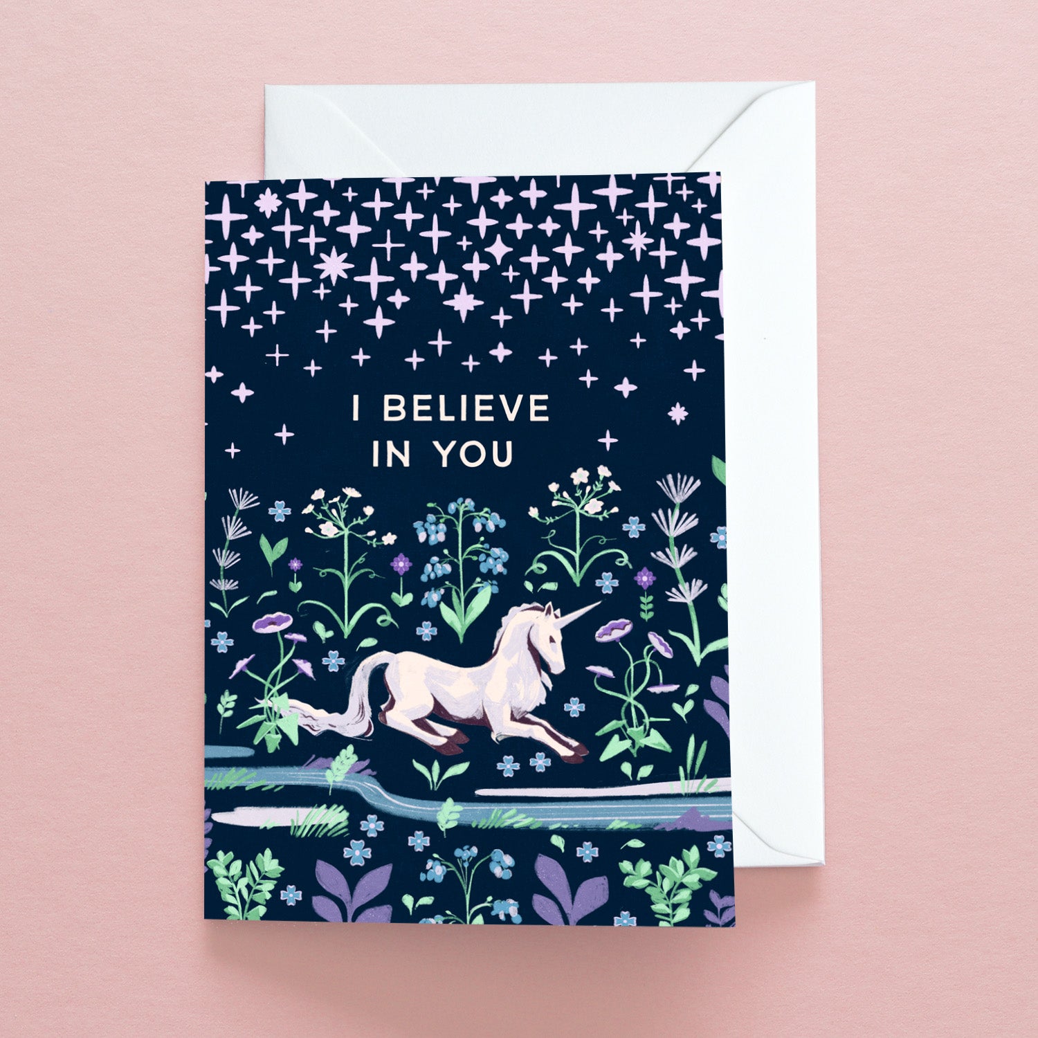 The Papio Press I Believe in you Unicorn Greetings Card features a unicorn running through flowers under a starry night sky on a pink background, with the message I BELIEVE IN YOU. Printed on recycled stock with an envelope included.