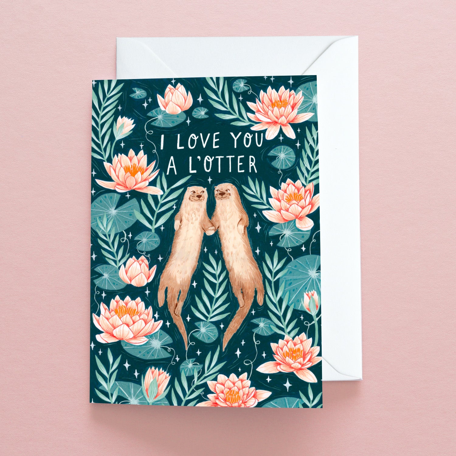 The Papio Press I Love You A LOtter Greetings Card shows two otters holding paws among lotus flowers on a pink surface, with an envelope behind. Printed on recycled stock, it reads I LOVE YOU A LOTTER.