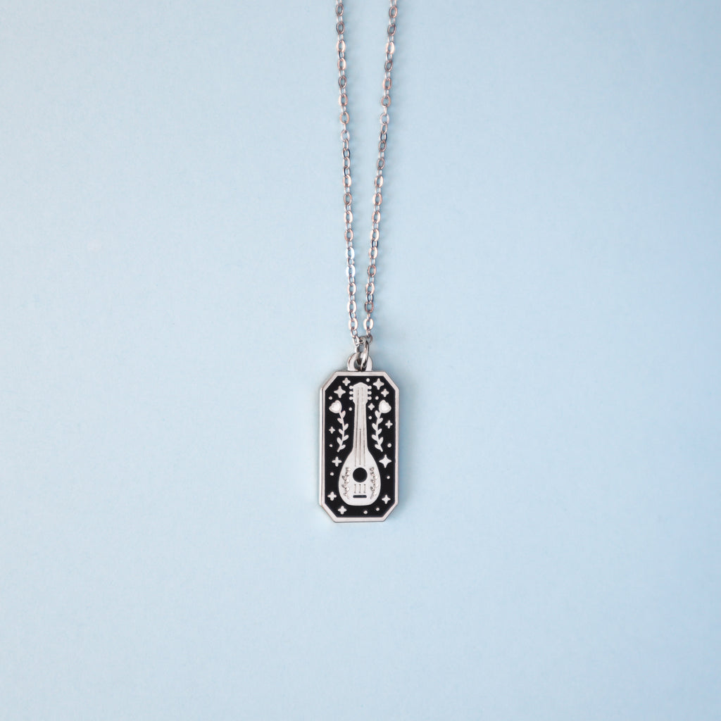 A silver bard necklace on a light blue background.