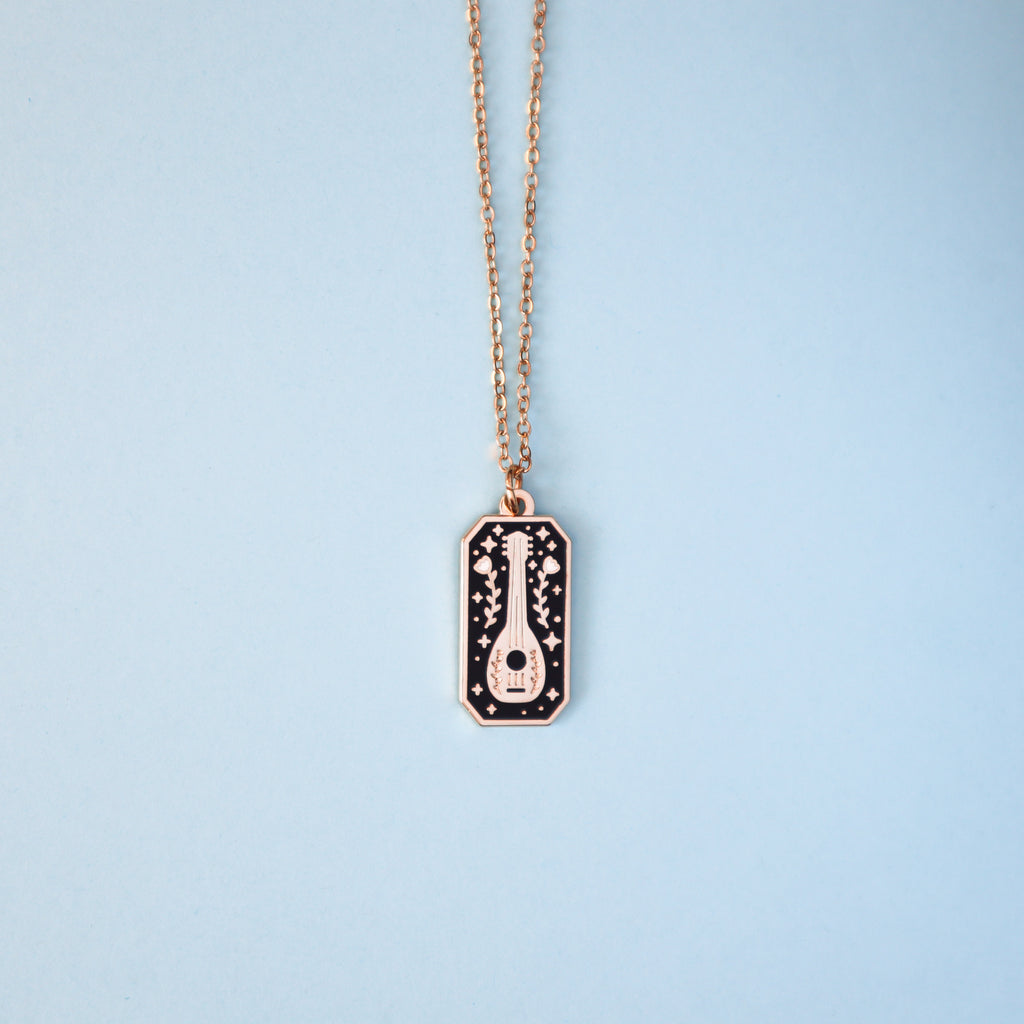 A gold bard necklace on a light blue background.