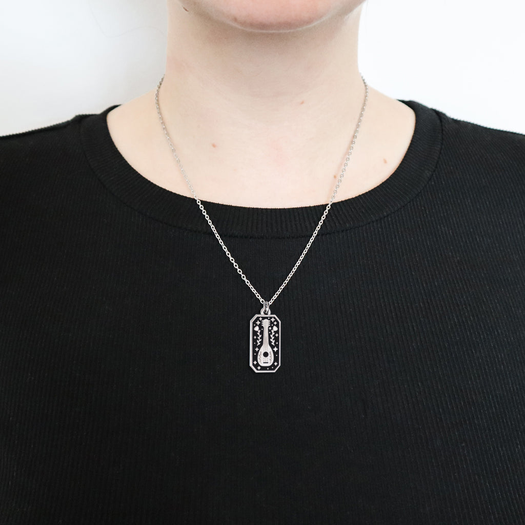A silver bard necklace being worn by a woman wearing a black top.