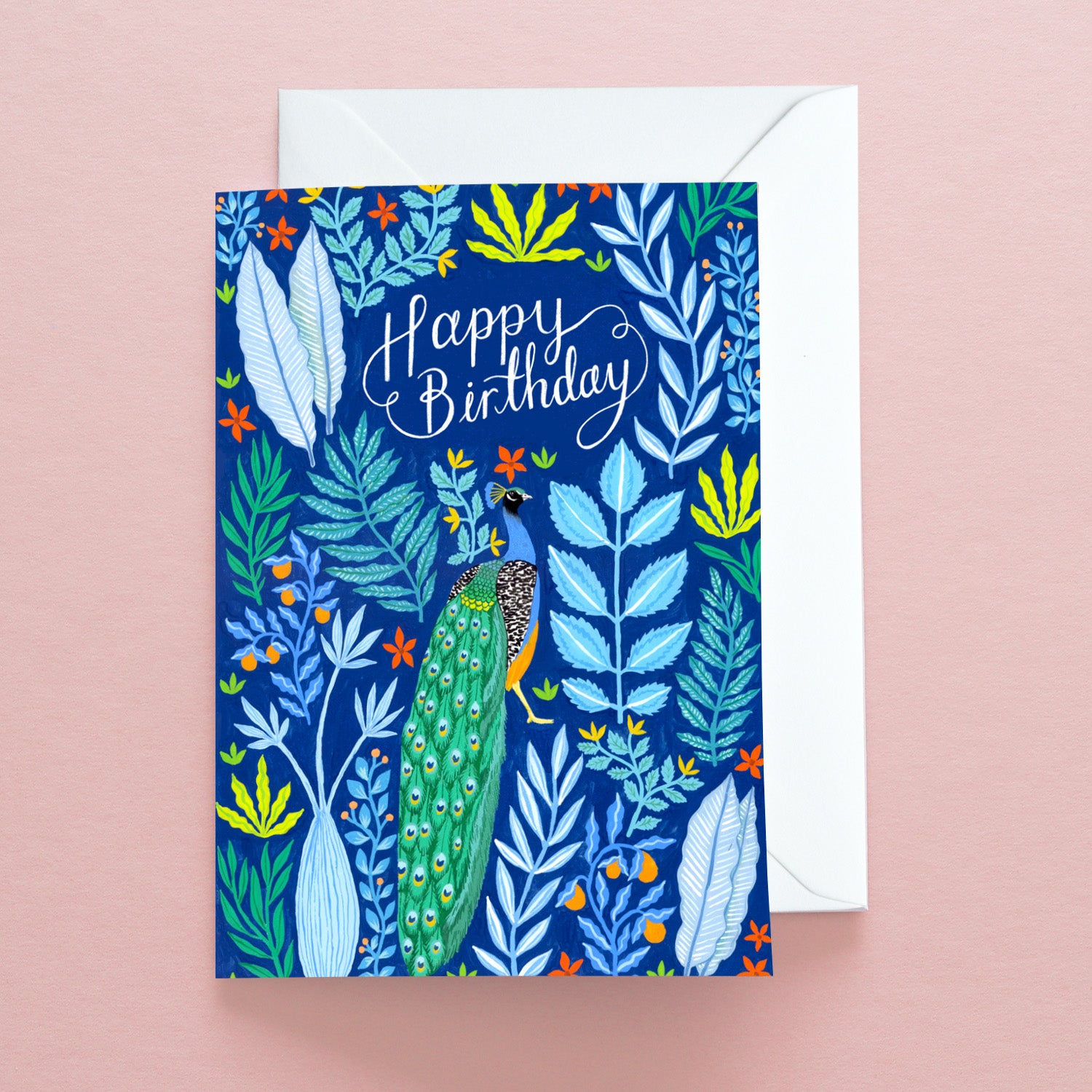 The Happy Birthday Peacocks Greetings Card by Papio Press features vibrant peacocks and colorful leaves on a pale pink background. Printed on recycled stock, it comes with a white envelope.