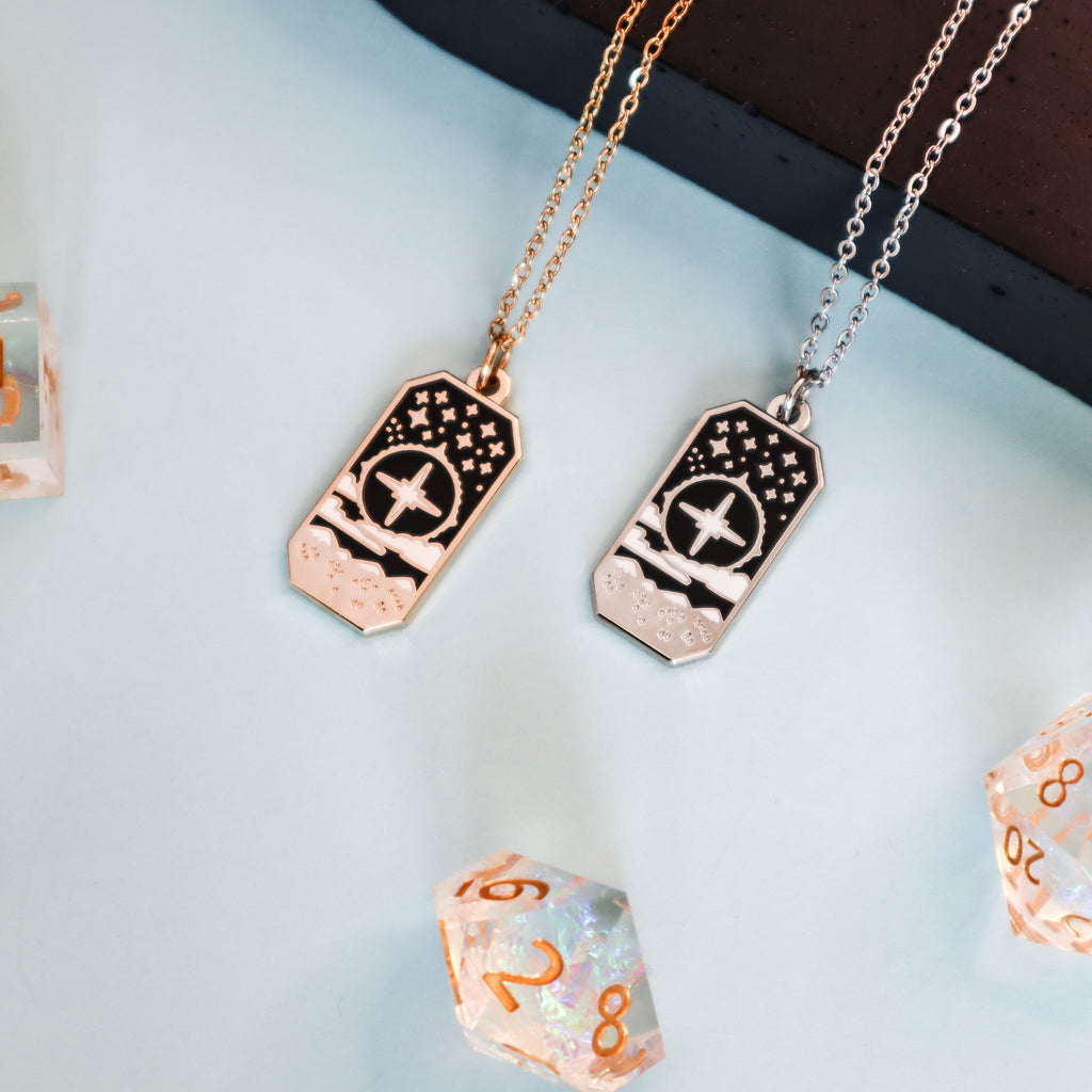 Two Cleric necklaces on a light blue background. The necklaces are rectangular in shape and feature a large star with mountains and clouds.
