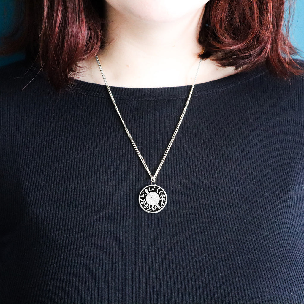 A silver crochet necklace being worn by a model wearing a black top.