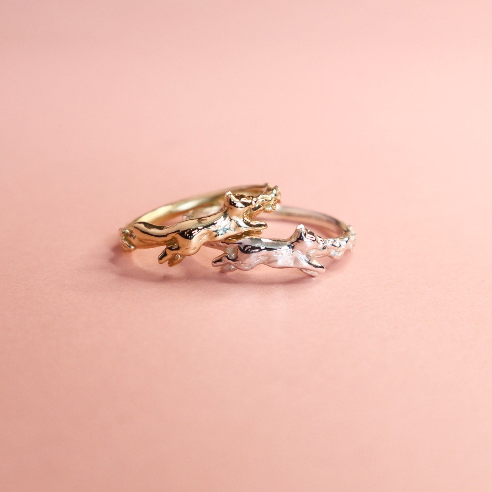 Two fox rings, one gold and one silver a pink background