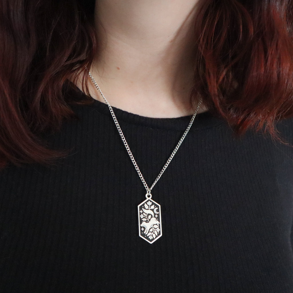 A silver floral fox necklace being worn by a model wearing a black top.
