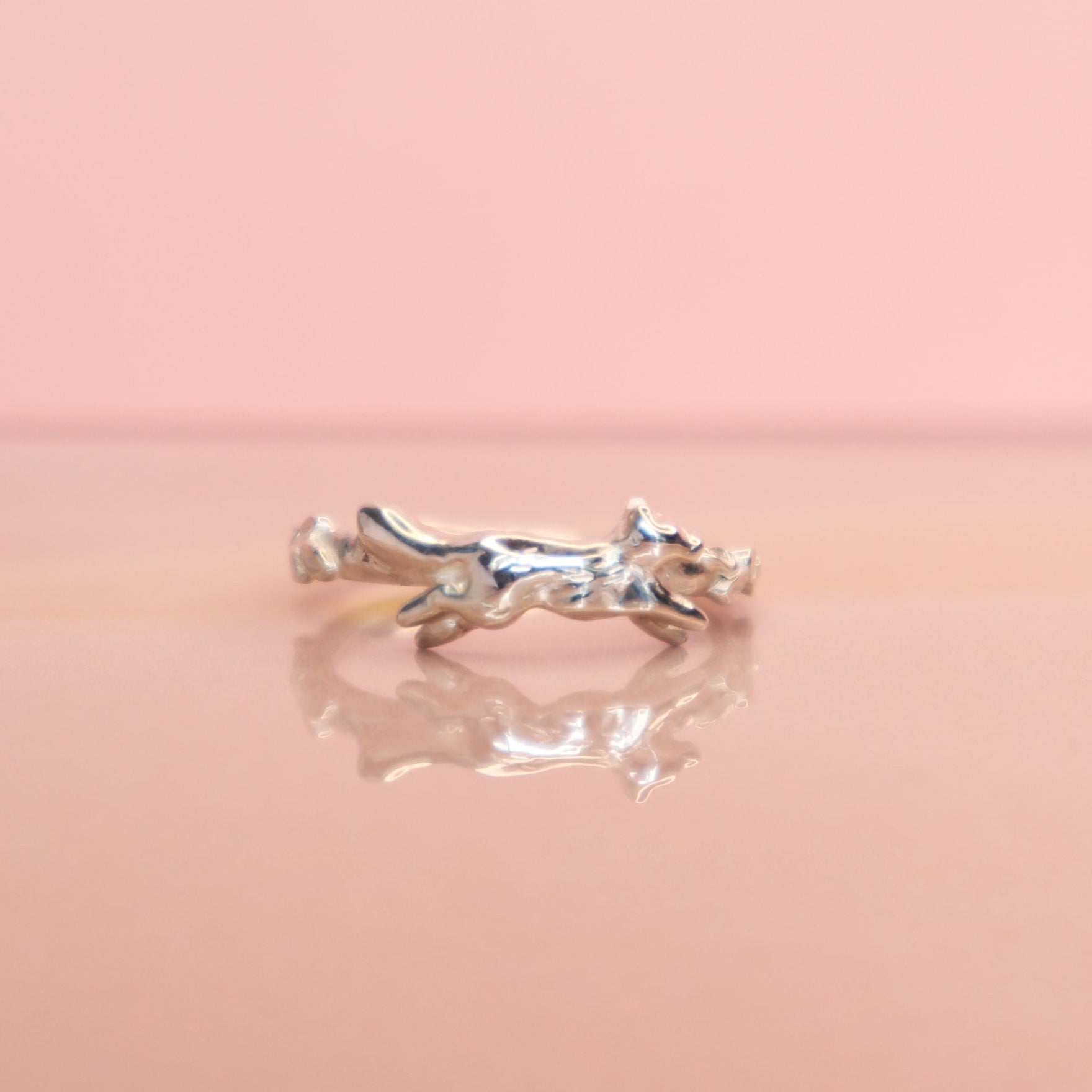 A silver fox ring taken on a polished pink background. 