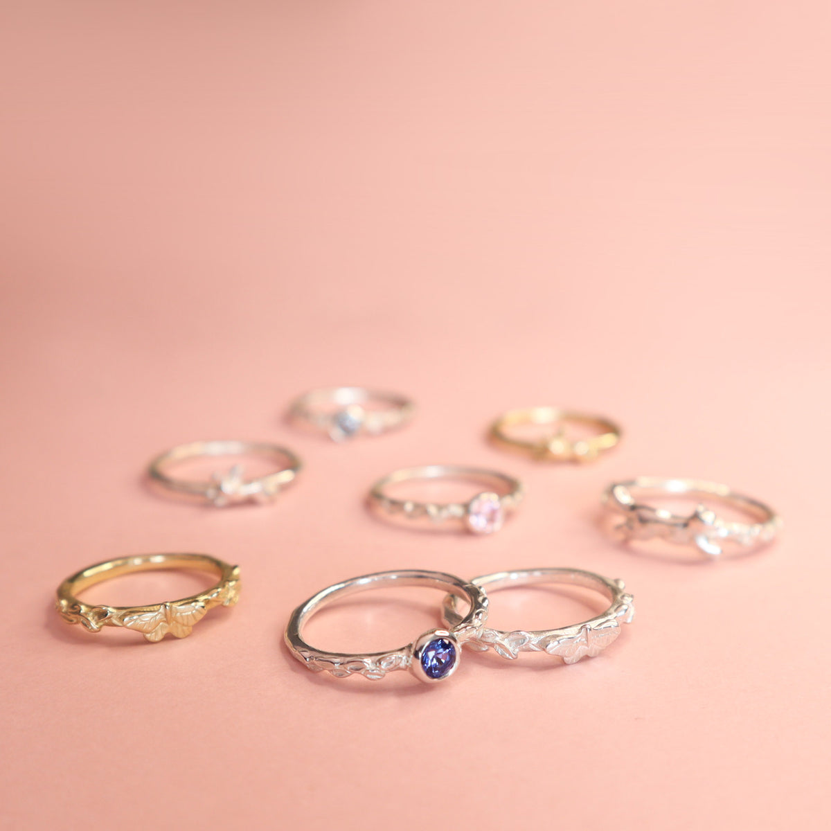 A selection of Papio Press rings on a light pink background. 