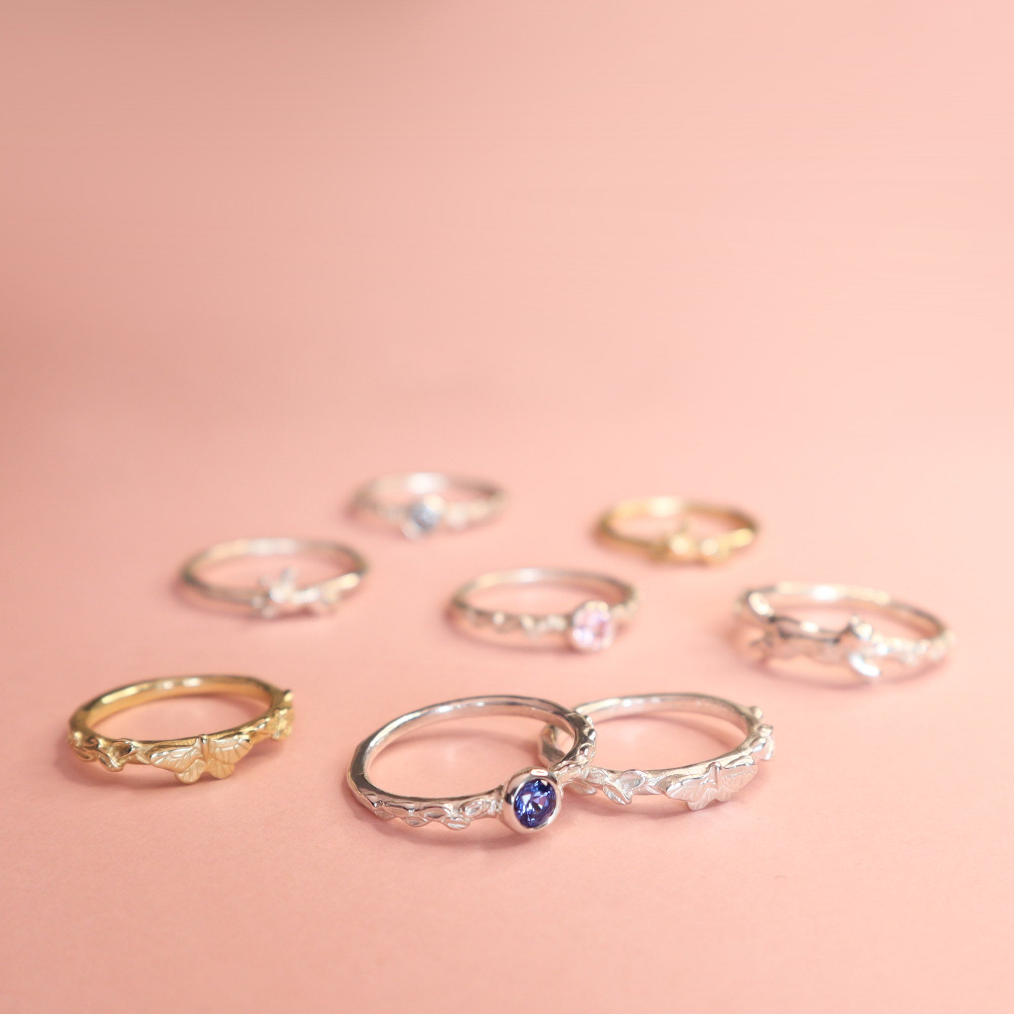 A selection of Papio Press rings on a light pink background. 