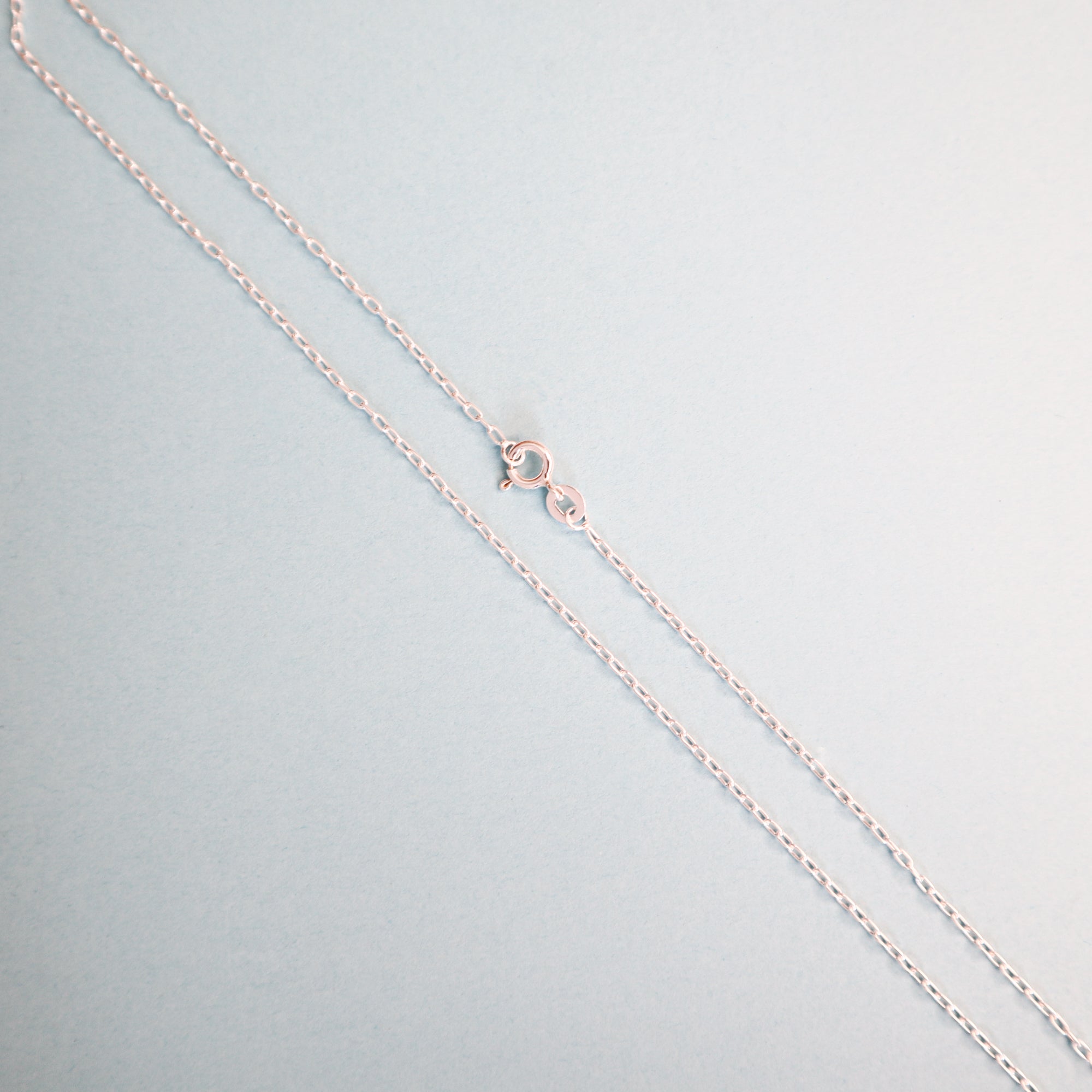 A  silver cable link chain on a light blue background. 