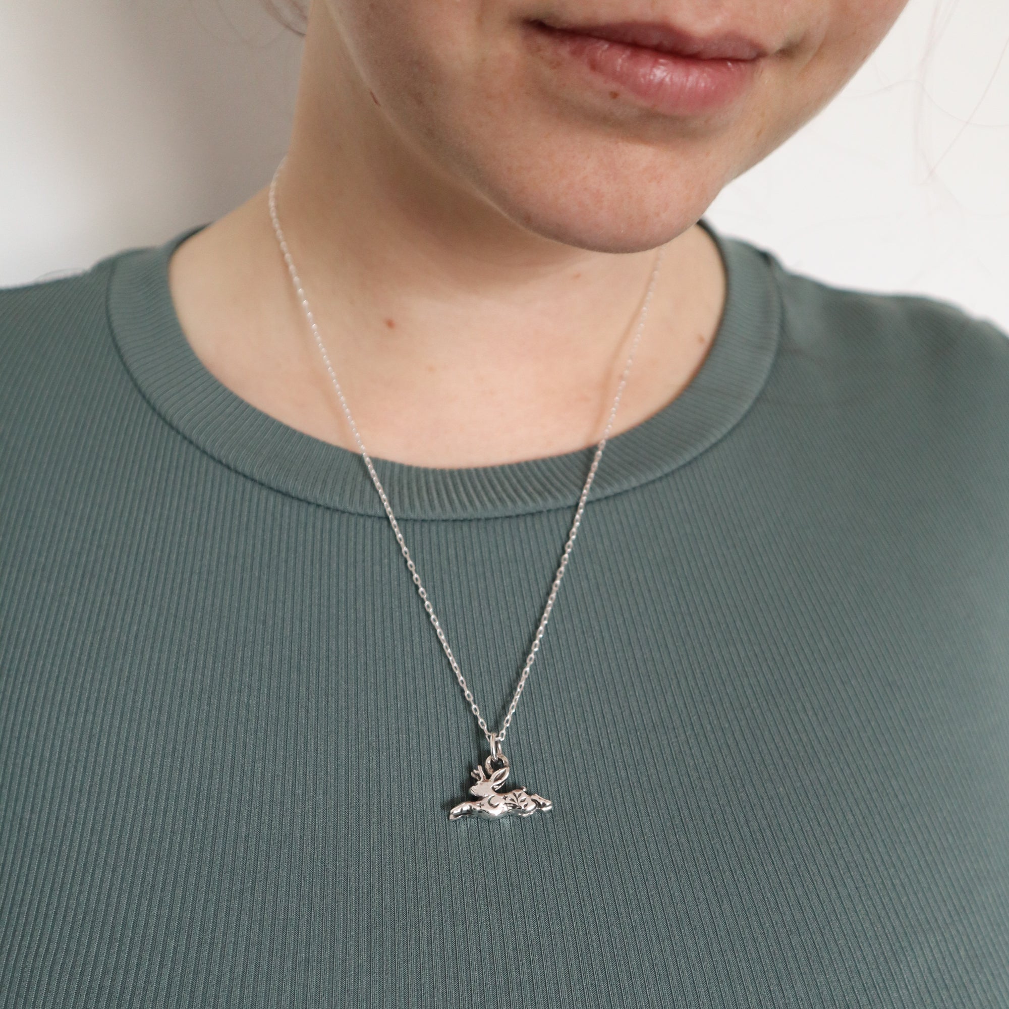 A woman wearing a silver jackalope necklace.
