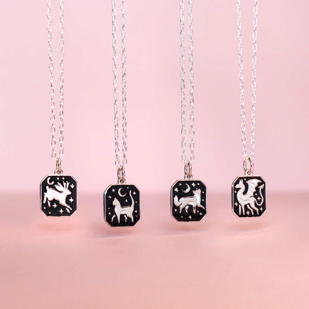A selection Papio Press sterling necklaces, hanging on a soft pink background. 