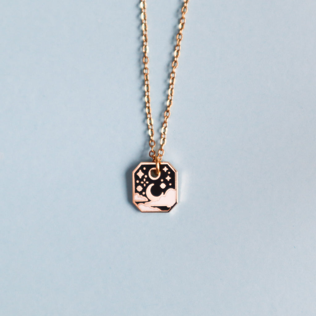 A gold starry sky necklace on a light blue background.