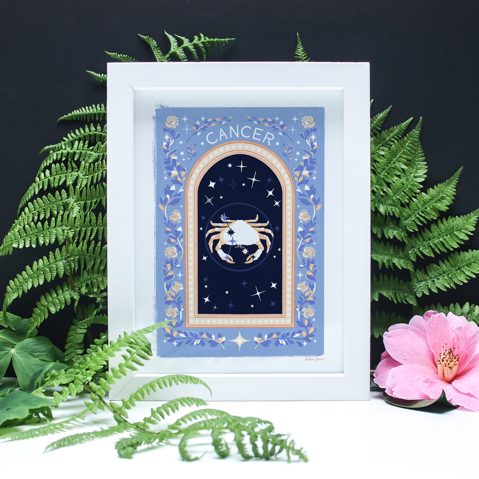Papio Press Choose your own Constellation Print // Star Signs features a Cancer crab with stars, blue and gold borders, fern leaves, and a pink flower on black—archival satin paper ensures lasting beauty. Framed zodiac art print.