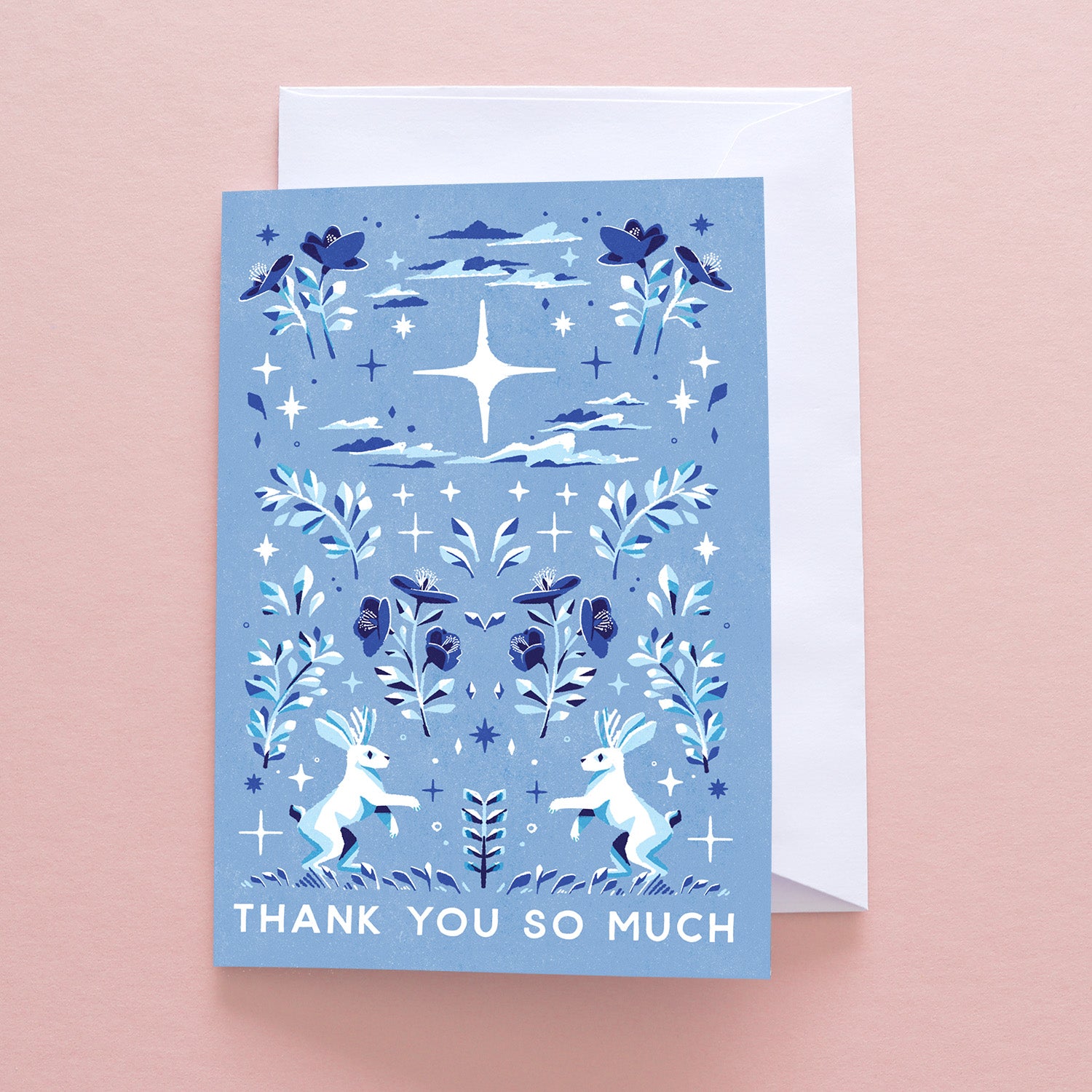The Papio Press Thank You So Much Jackalope greetings card features plants, clouds, stars, and two white jackalopes on a light pink background with white text; comes with a white envelope and is printed on recycled stock.