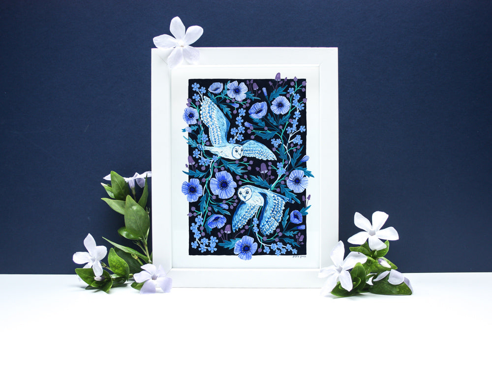 The Night Owls Artists Print by Papio Press showcases two white and blue owls flying among blue and purple flowers on a dark background with white flowers and green leaves, printed on archival satin paper. Designed in the UK.